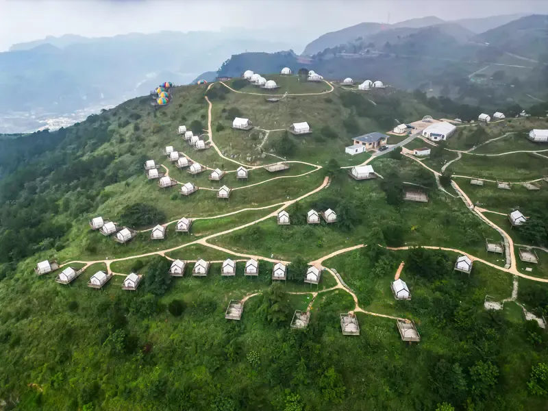 百里荒山顶露营区航拍,白色帐篷散落在绿色山头