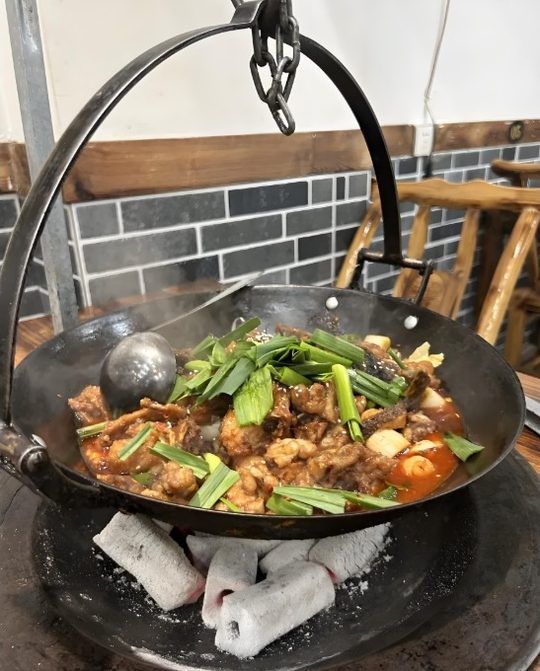 罗田吊锅实拍:铸铁锅悬在炭火上咕嘟慢炖。