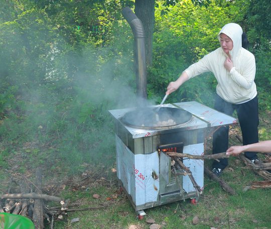 灶台边有人掌勺、有人添柴，一桌饭一起完成